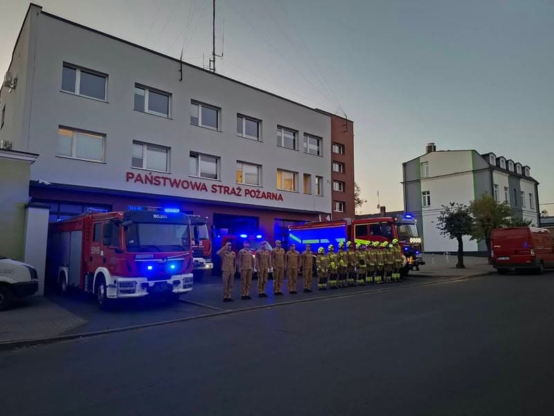 Strażacy i samochody ratownicze przed komendą PSP w Poddębicach podczas hołdu