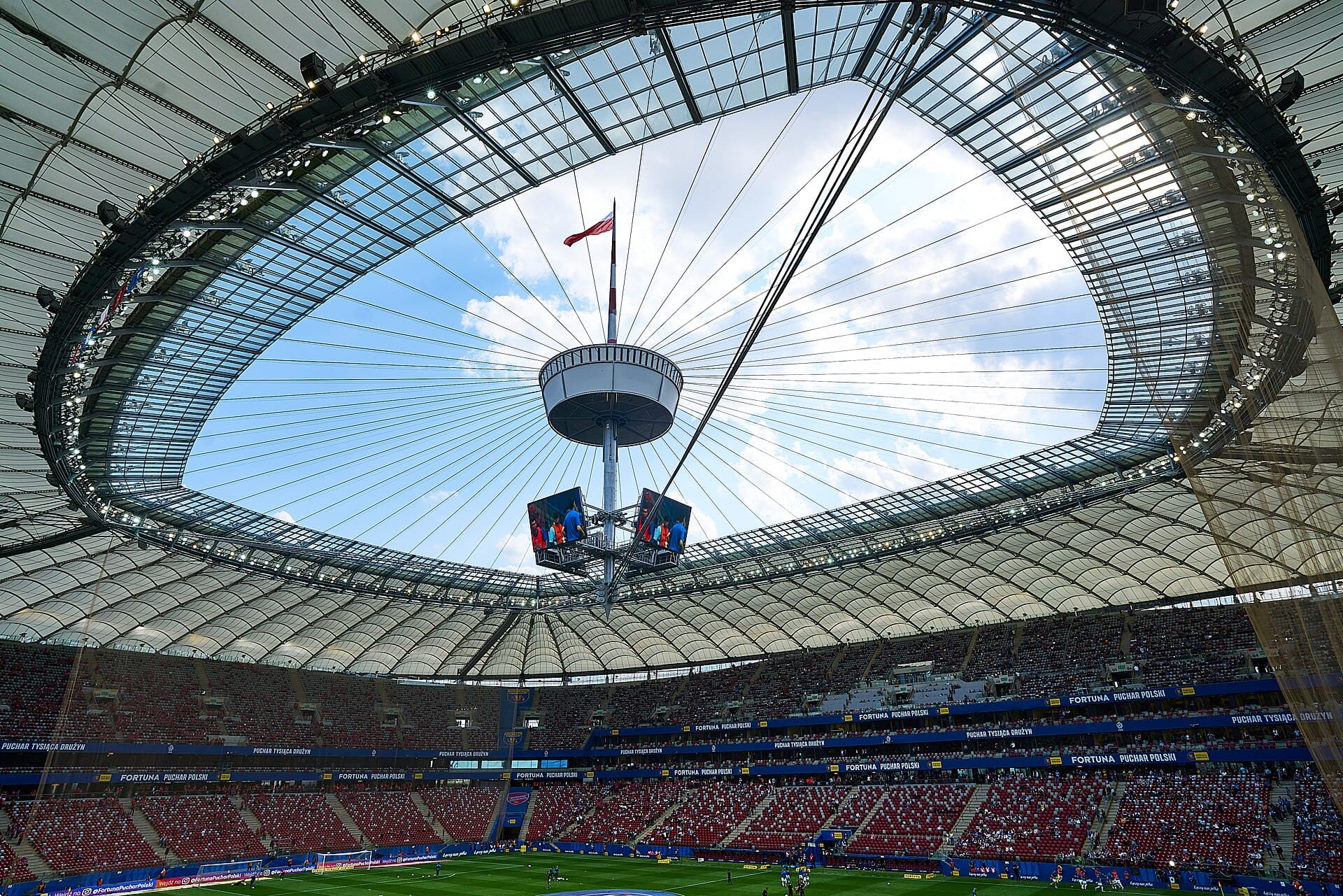 Wnętrze PGE Narodowego w Warszawie z polską flagą pod dachem stadionu