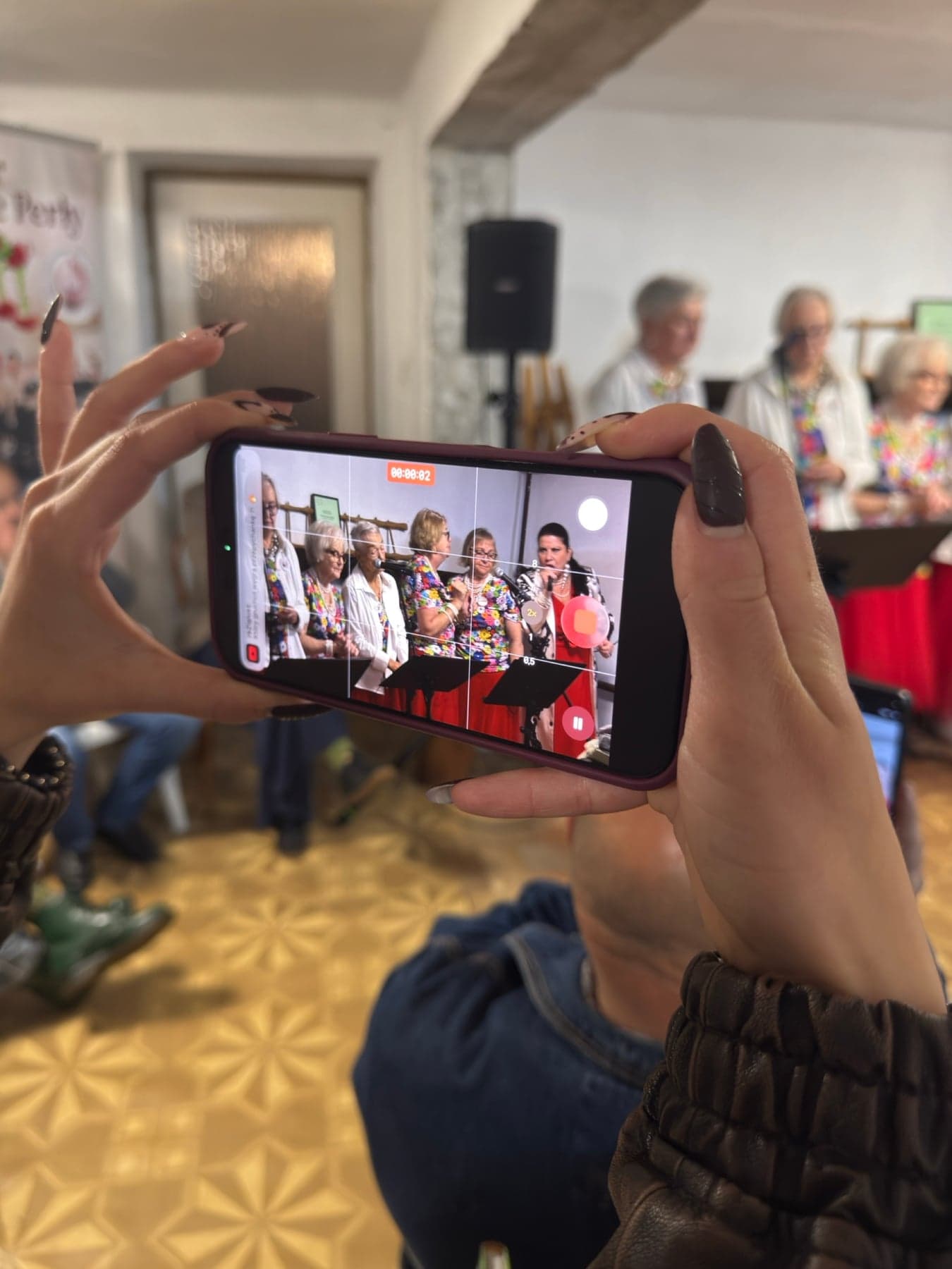 Chór Muzyczne Perły z Anną Cymmerman śpiewa podczas Pikniku Wolontariatu, widz nagrywa występ telefonem